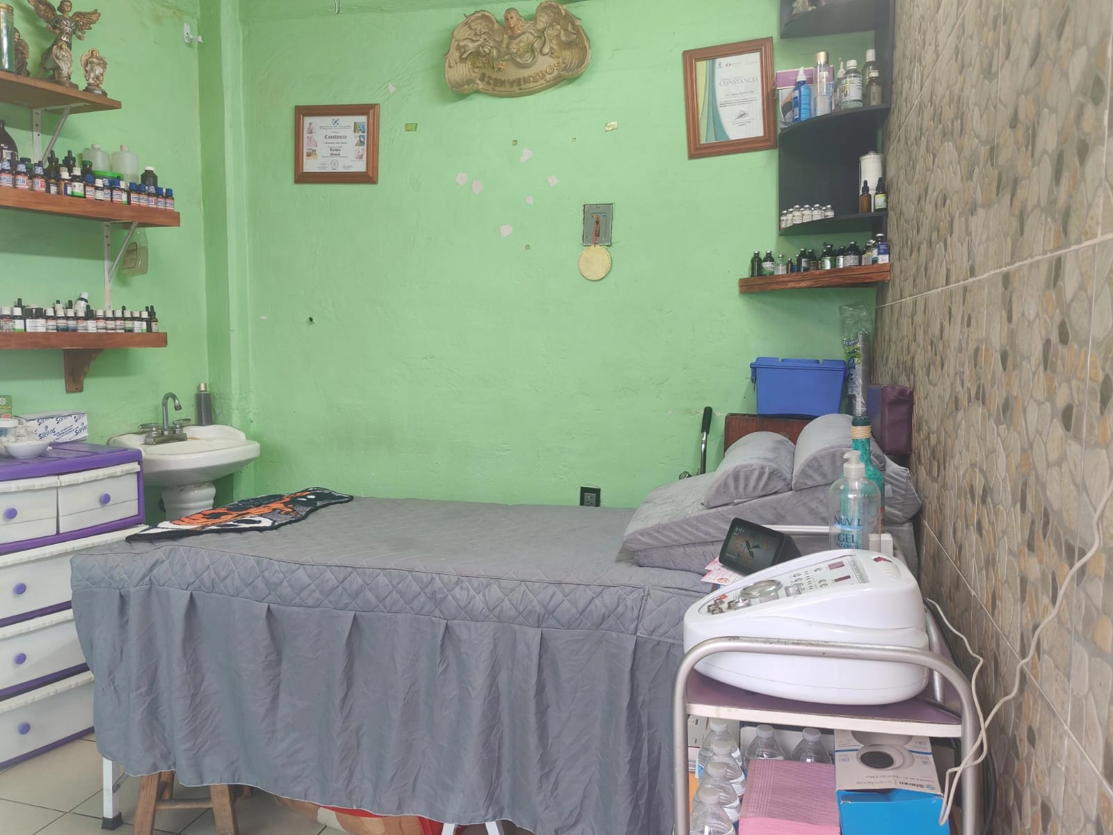 Cabina de terapias y estética del consultorio de Mercado Concordia, con camilla acolchada, repisas con esencias y equipo de estética